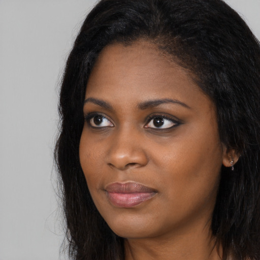 Joyful black young-adult female with long  brown hair and brown eyes