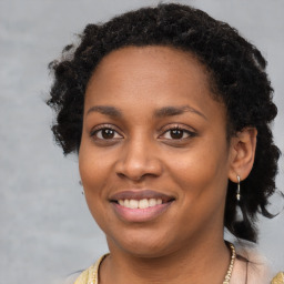 Joyful black young-adult female with long  brown hair and brown eyes