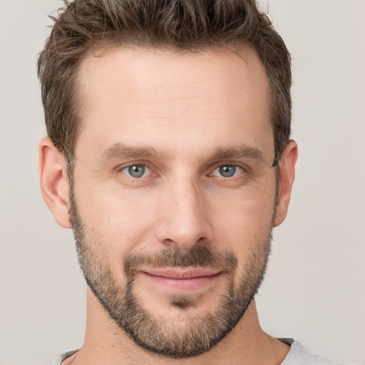 Joyful white young-adult male with short  brown hair and grey eyes