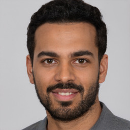 Joyful latino young-adult male with short  black hair and brown eyes