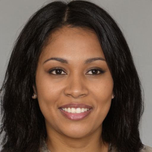 Joyful black young-adult female with long  brown hair and brown eyes