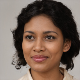 Joyful black young-adult female with medium  brown hair and brown eyes