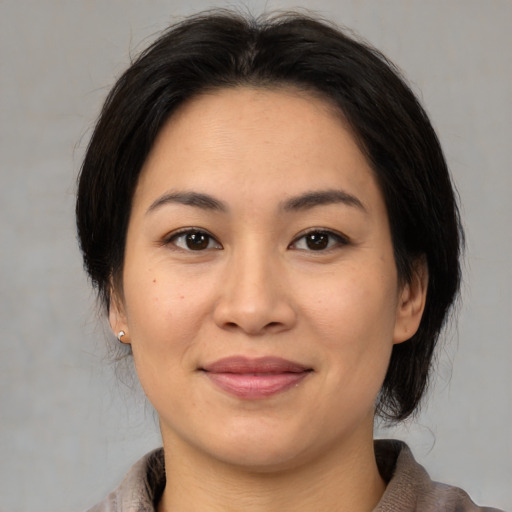 Joyful asian adult female with medium  brown hair and brown eyes