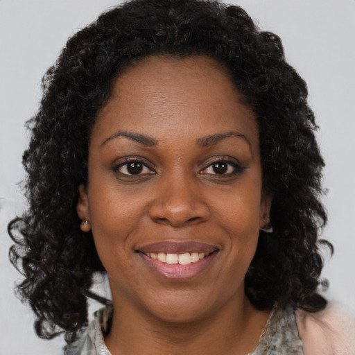 Joyful black young-adult female with long  brown hair and brown eyes