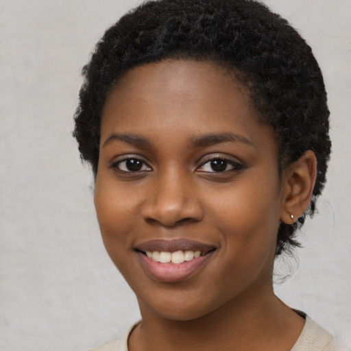 Joyful black young-adult female with short  black hair and brown eyes