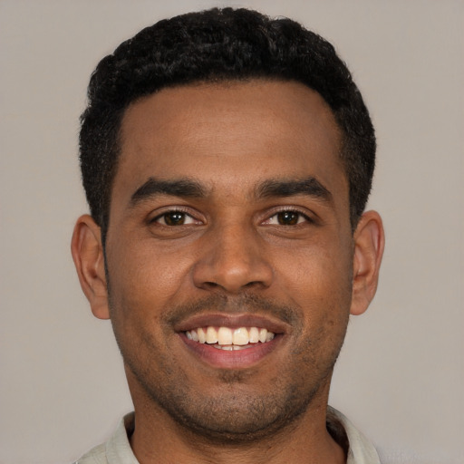 Joyful black young-adult male with short  brown hair and brown eyes
