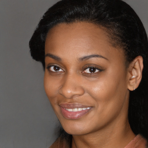 Joyful black young-adult female with long  black hair and brown eyes
