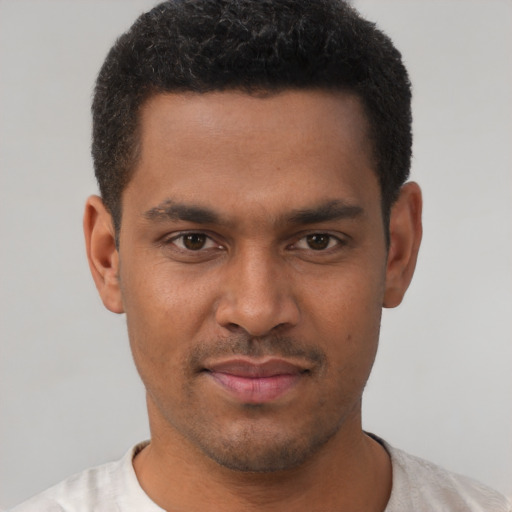 Joyful black young-adult male with short  brown hair and brown eyes