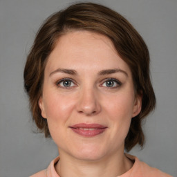 Joyful white young-adult female with medium  brown hair and grey eyes