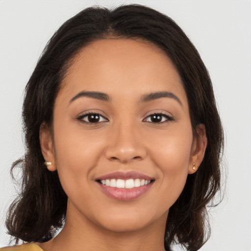 Joyful latino young-adult female with long  brown hair and brown eyes