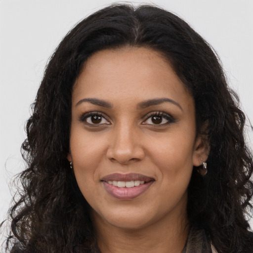 Joyful black young-adult female with long  brown hair and brown eyes