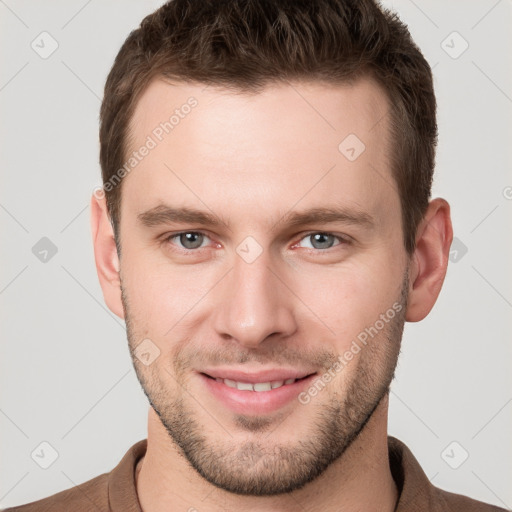 Joyful white young-adult male with short  brown hair and grey eyes