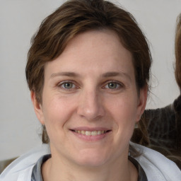 Joyful white young-adult female with medium  brown hair and grey eyes