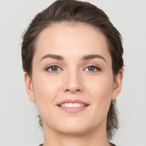 Joyful white young-adult female with medium  brown hair and grey eyes