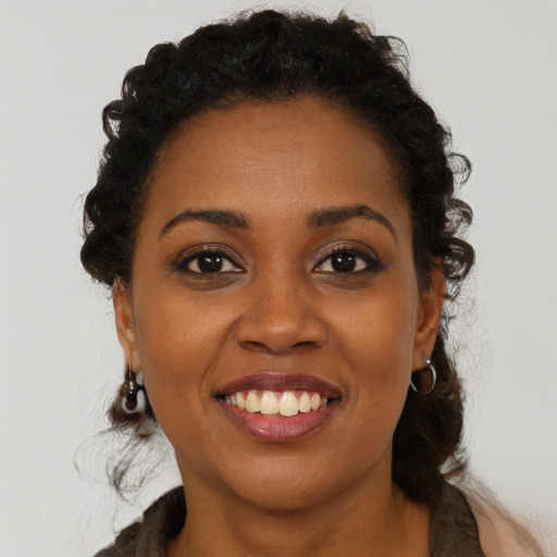 Joyful black young-adult female with long  brown hair and brown eyes