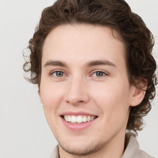 Joyful white young-adult male with short  brown hair and green eyes