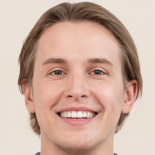 Joyful white young-adult male with short  brown hair and grey eyes