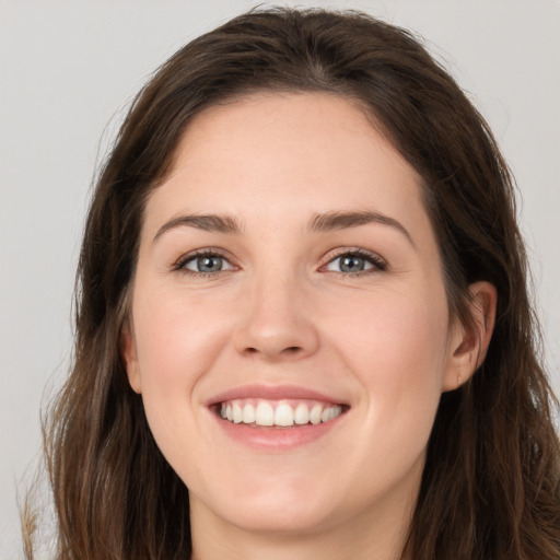 Joyful white young-adult female with long  brown hair and grey eyes