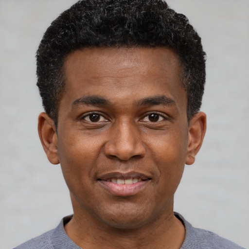 Joyful black young-adult male with short  black hair and brown eyes