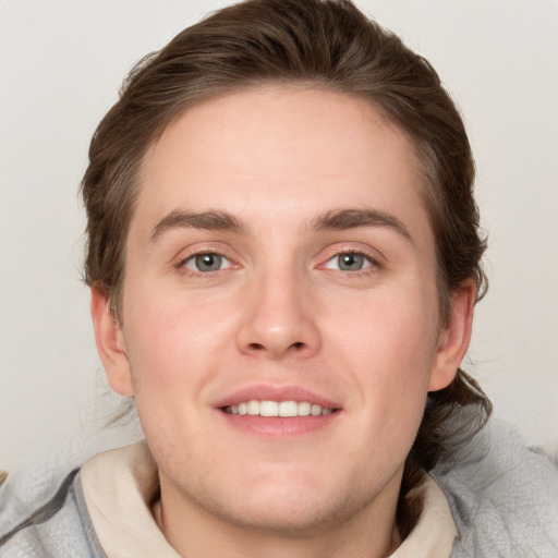 Joyful white young-adult male with short  brown hair and blue eyes