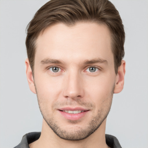 Joyful white young-adult male with short  brown hair and grey eyes