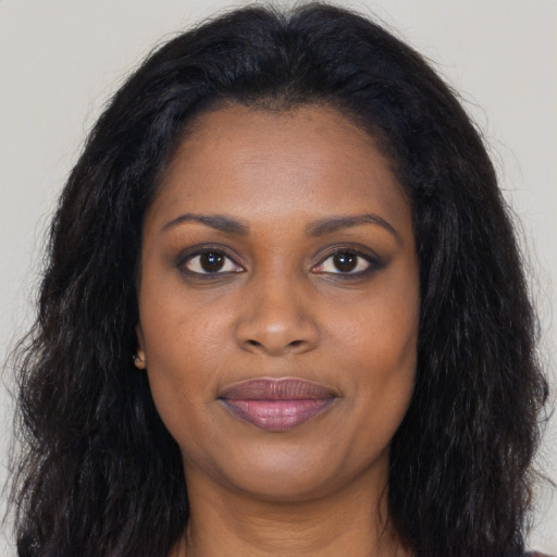 Joyful black young-adult female with long  black hair and brown eyes