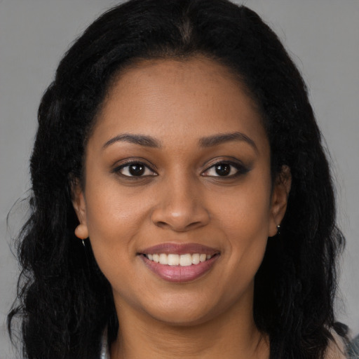 Joyful black young-adult female with long  brown hair and brown eyes