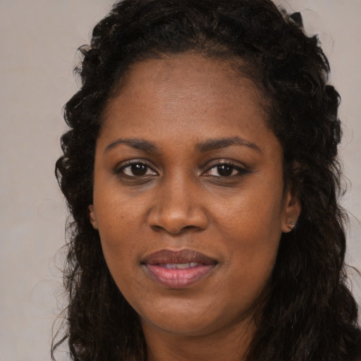 Joyful black adult female with long  brown hair and brown eyes