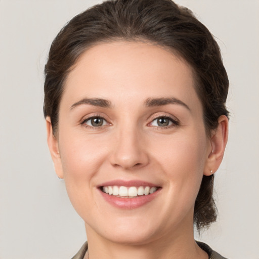 Joyful white young-adult female with medium  brown hair and grey eyes