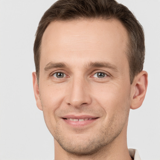 Joyful white young-adult male with short  brown hair and grey eyes