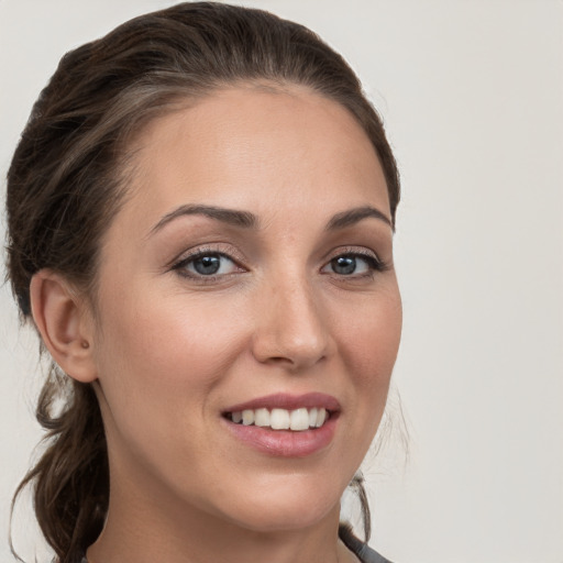 Joyful white young-adult female with medium  brown hair and grey eyes