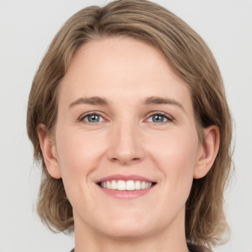 Joyful white young-adult female with medium  brown hair and grey eyes