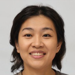 Joyful asian young-adult female with medium  brown hair and brown eyes