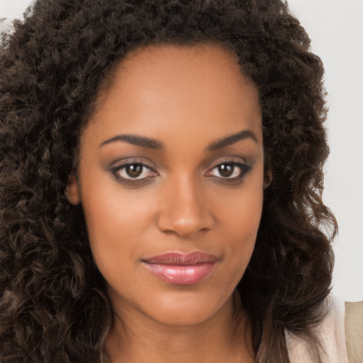 Joyful black young-adult female with long  brown hair and brown eyes