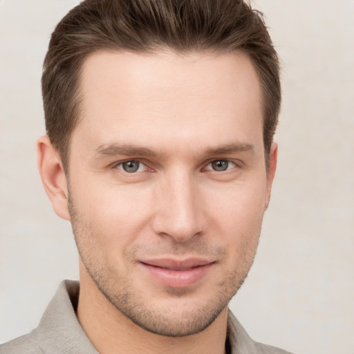 Joyful white young-adult male with short  brown hair and grey eyes