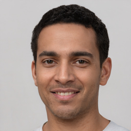 Joyful latino young-adult male with short  black hair and brown eyes