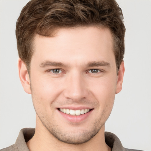 Joyful white young-adult male with short  brown hair and grey eyes