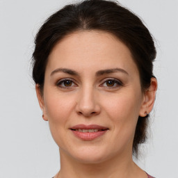 Joyful white young-adult female with medium  brown hair and grey eyes