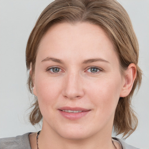 Joyful white young-adult female with medium  brown hair and blue eyes