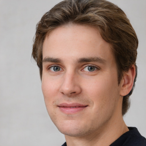 Joyful white young-adult male with short  brown hair and grey eyes