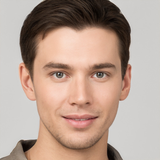 Joyful white young-adult male with short  brown hair and grey eyes