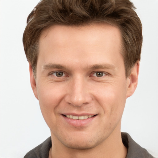 Joyful white young-adult male with short  brown hair and grey eyes