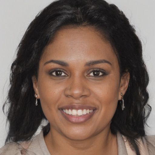 Joyful black young-adult female with long  brown hair and brown eyes