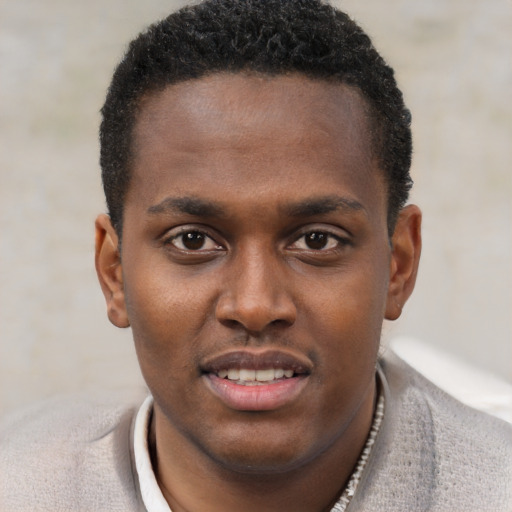 Joyful black young-adult male with short  brown hair and brown eyes