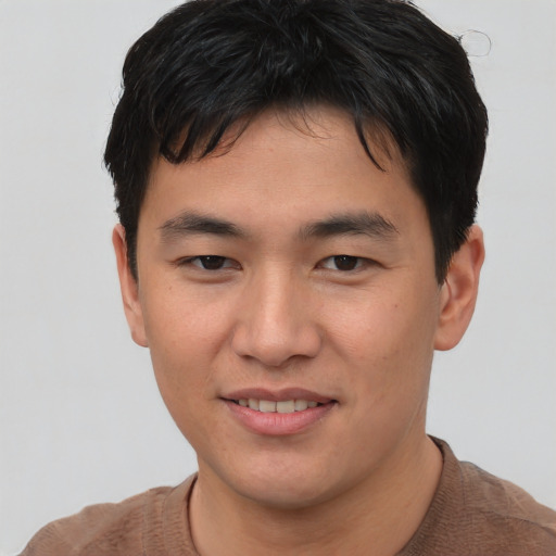 Joyful asian young-adult male with short  brown hair and brown eyes