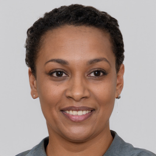 Joyful black young-adult female with short  black hair and brown eyes