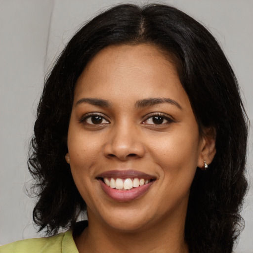 Joyful black young-adult female with long  black hair and brown eyes