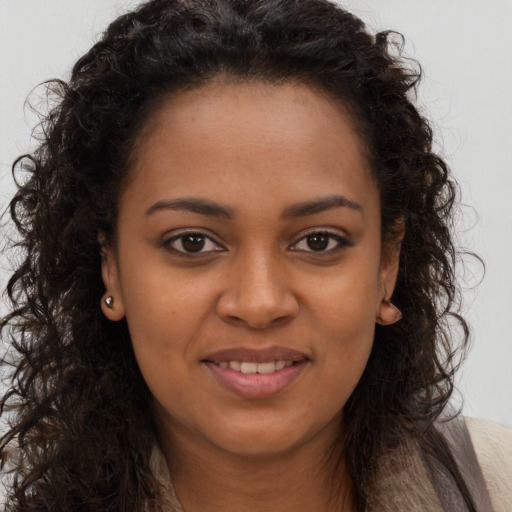 Joyful black young-adult female with long  brown hair and brown eyes