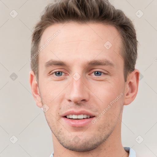 Joyful white young-adult male with short  brown hair and grey eyes