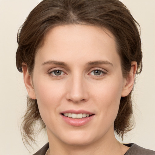 Joyful white young-adult female with medium  brown hair and grey eyes